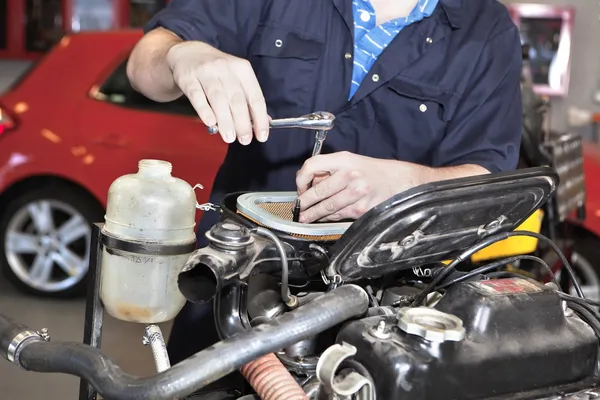 Man holding a spanner over a car engine