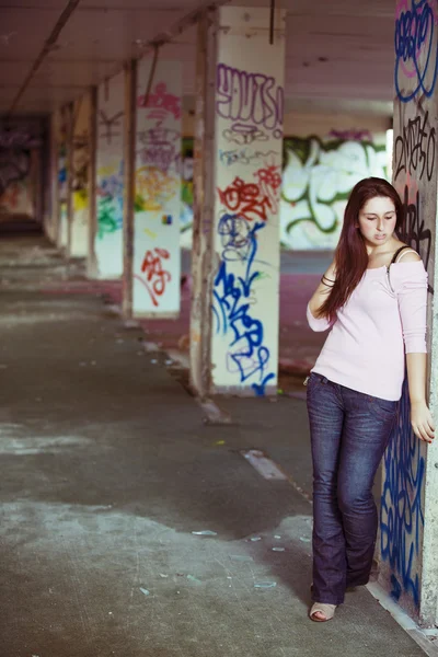 Young pretty girl posing in abandoned graffiti painted building