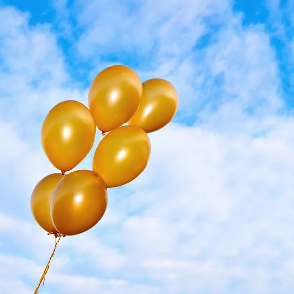 Golden flying balloons on the sky background