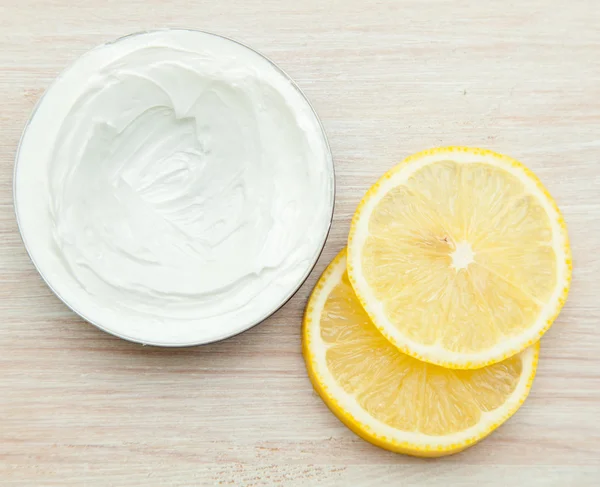 Body cream and lemon slices on the wooden table