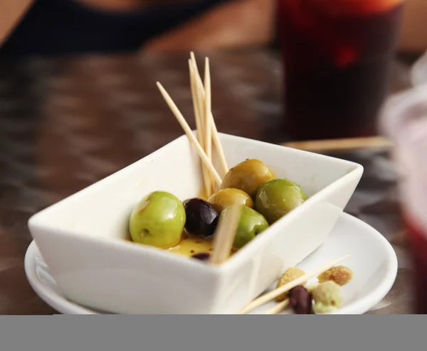Large green and black olives in a plate on a table