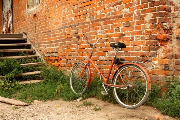 Old bicycle on the background of red brick walls