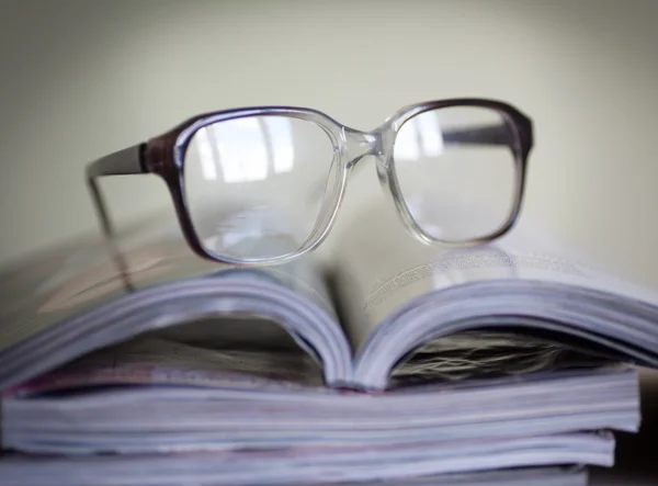 Glasses for reading on a stack of magazines, in soft focus