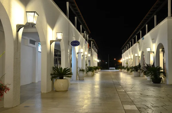 The brightly illuminated night street with light arches and walls, and a marble pavement