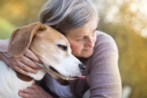 Active senior woman hugs dog