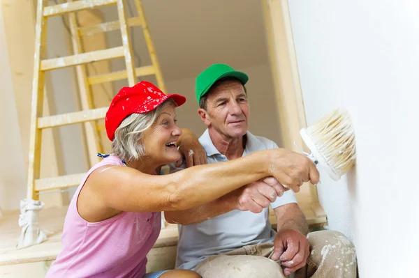 Senior couple painting wall with brush