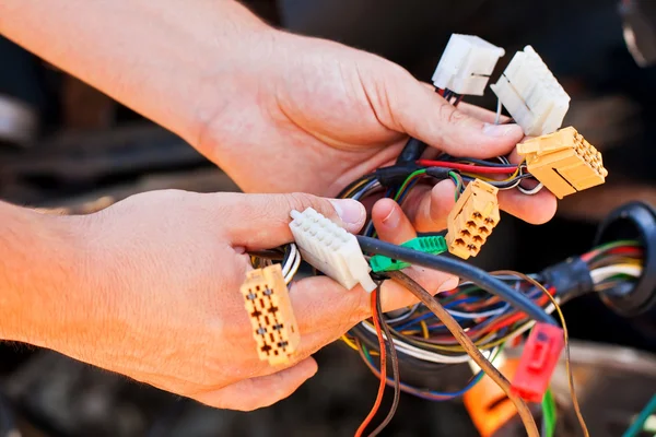 The young electrician man holds the wires