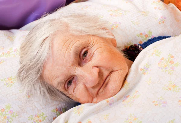 Elderly lonely woman rests in the bed