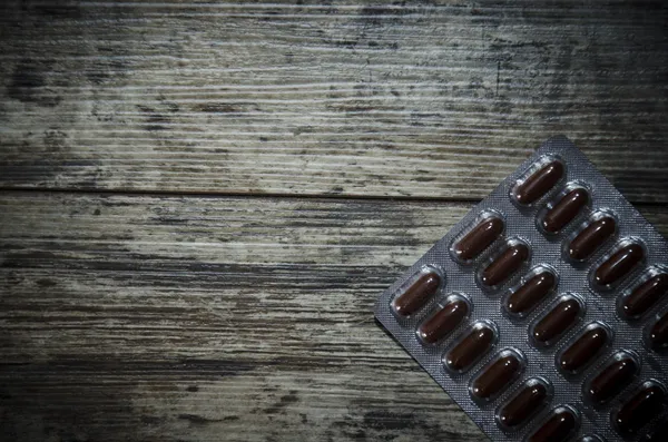 Medical pill on old wooden table. Close up photo