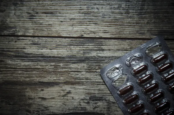 Medical pill on old wooden table. Close up photo