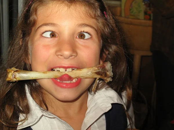 Girl with crossed eyes with bone in mouth