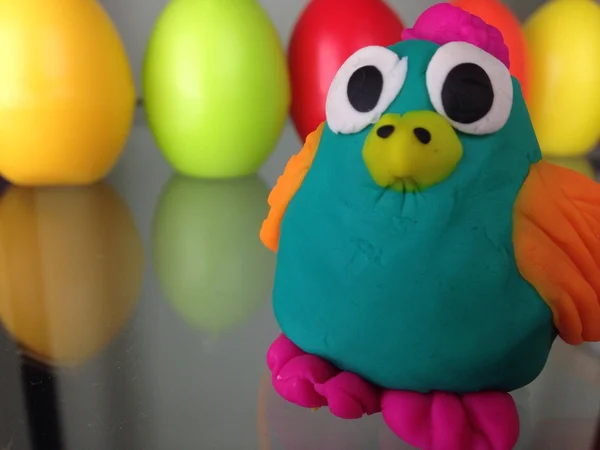 Funny owl made with kids play dough on the colorful eggs background, children craft and art ideas
