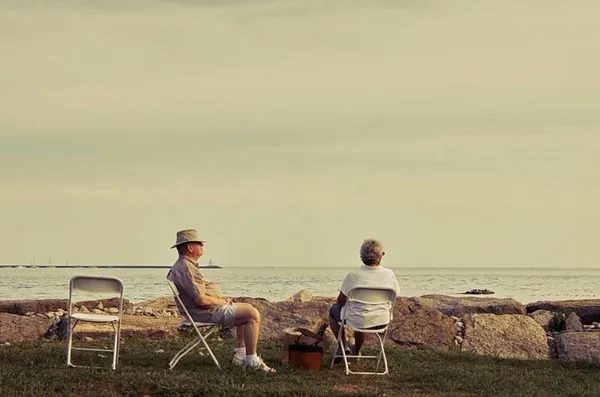 An old man and women rest at the ocean beach, retirement benefits