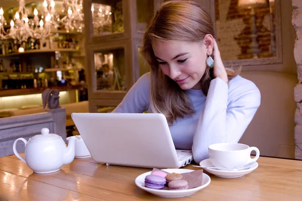 Smiling young woman with computer at breakfast