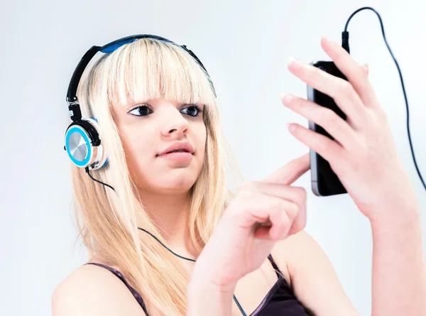 Attractive blond girl listening to music on her smartphone