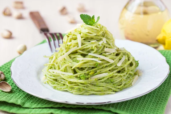 Italian green pasta spaghetti with pesto green peas, mint, pista