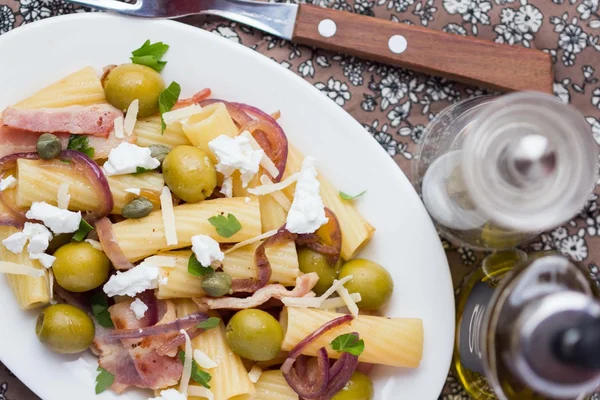 Rigatoni pasta with bacon, green olives, feta cheese, red onion,