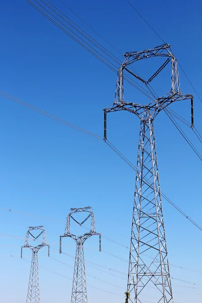 Three high voltage pylons under blue sky