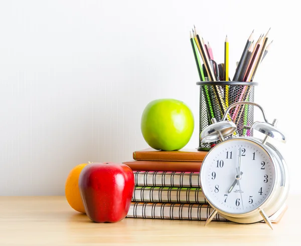 Note books , clock , pencils , apples