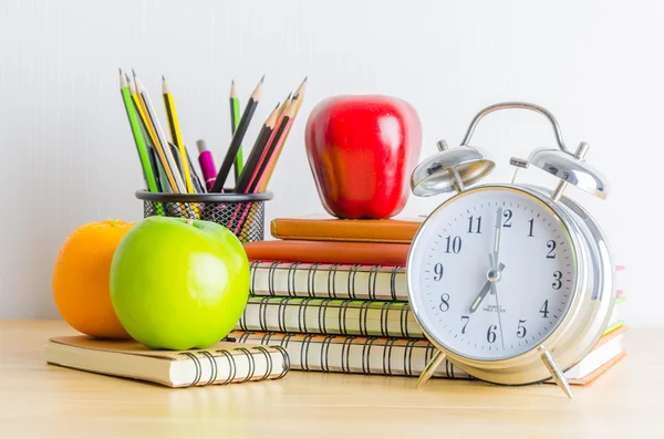 Note books , clock , pencils , apples