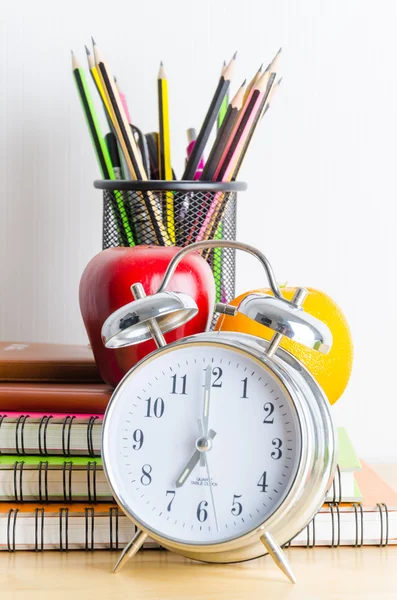 Note books, clock, pencils, apples