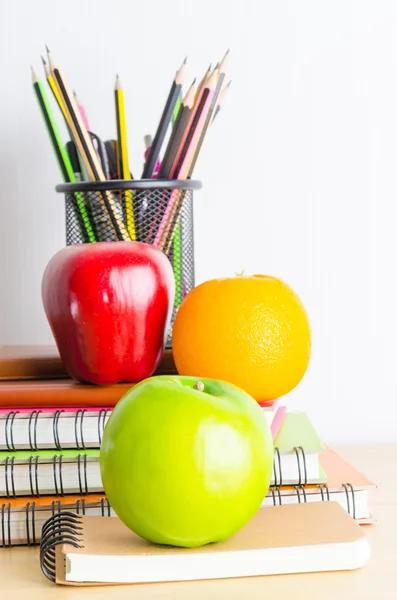 Note books,  pencils, apples on the table