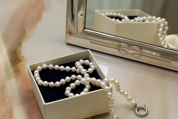 Pearl necklace in a gift box in front of a mirror