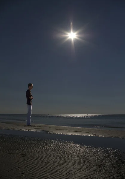 Lonely man stands on the sand and looking at the sea