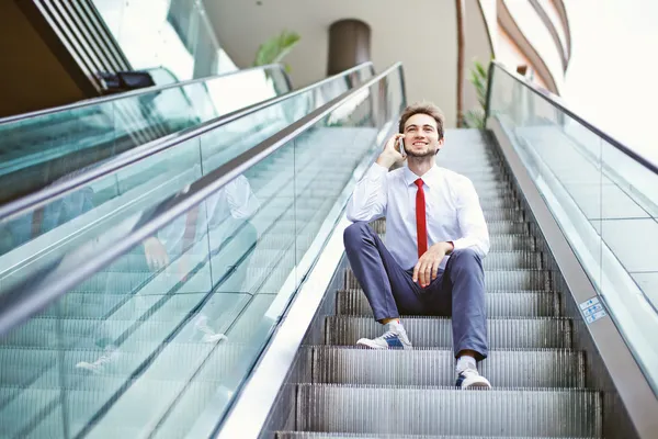 Businessman on an escalator stairs talking on mobile phone