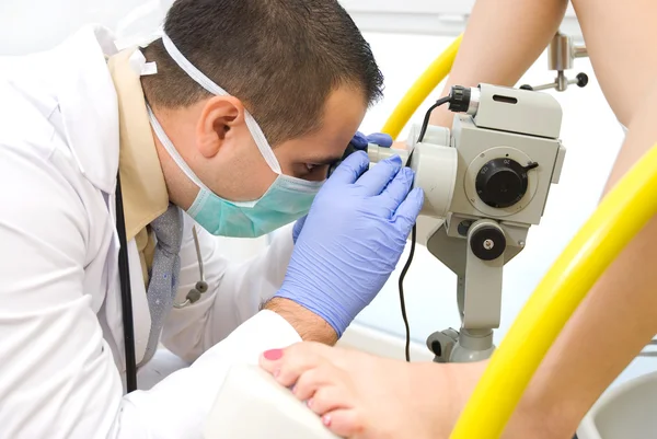Gynecologist examining a patient with a microscope