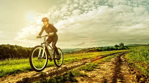 Sport bike woman on a meadow with a beautiful landscape