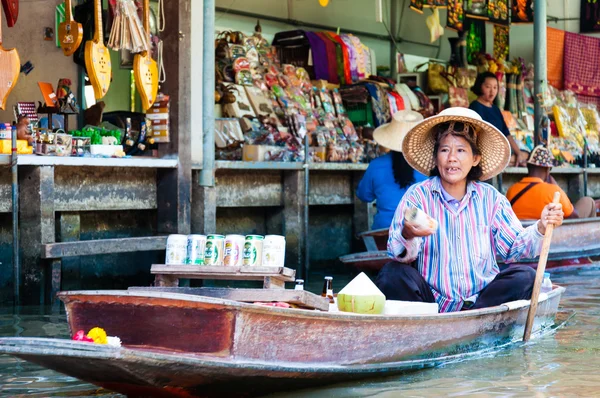 Ratchaburi, Thailand - May 24, 2014: Thai locals sell food and souvenirs at famous Damnoen Saduak floating market on  May 24, 2014 in Thailand, in the old traditional way of selling from small boats.