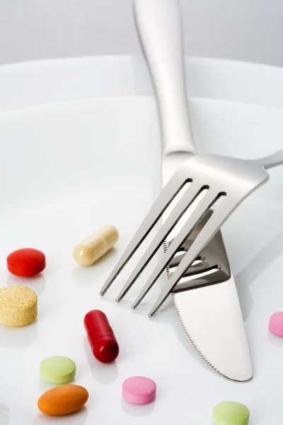 Fork, knife and many pills on a plate
