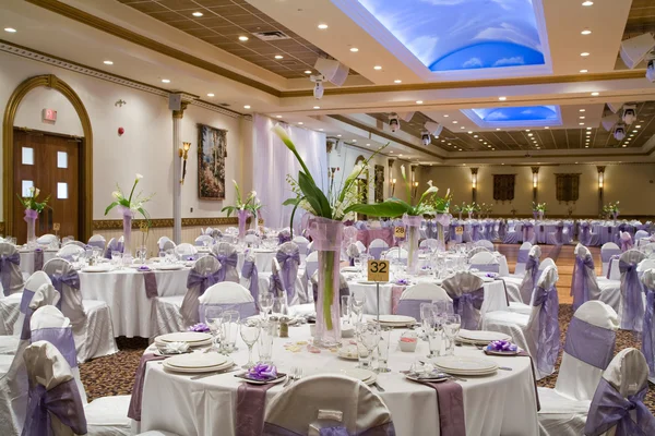 Indoor wedding reception hall with round tables and floral cent