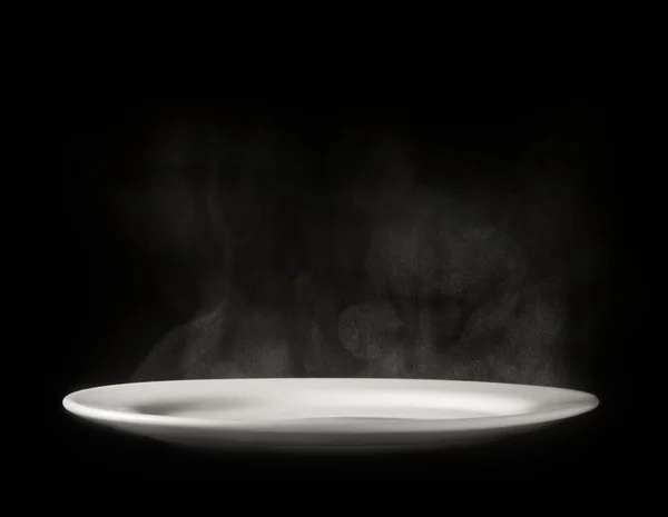White plate with steam on black background