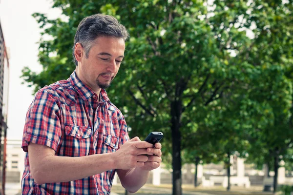 Man in short sleeve shirt texting on phone