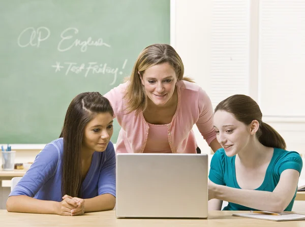 Teacher helping students on laptop