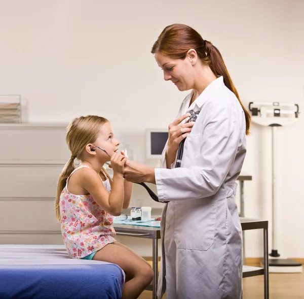 Doctor giving girl checkup in doctor office