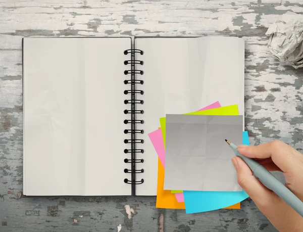 Sticky notes with open blank note book on desk top texture