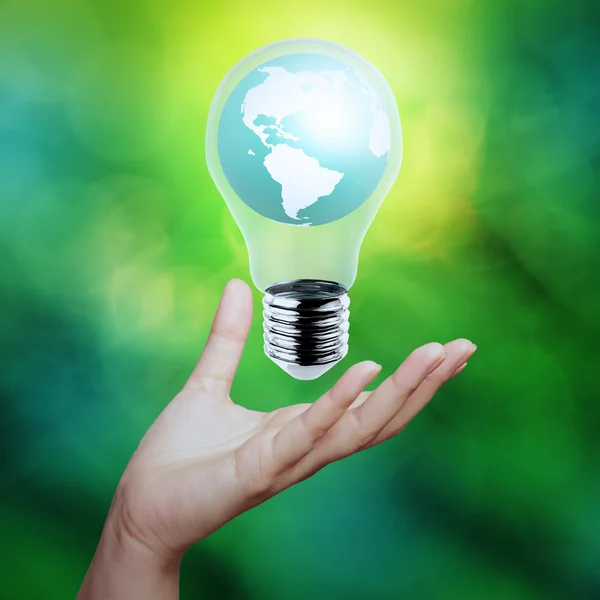 Hand holding planet earth in a lightbulb as energy concept