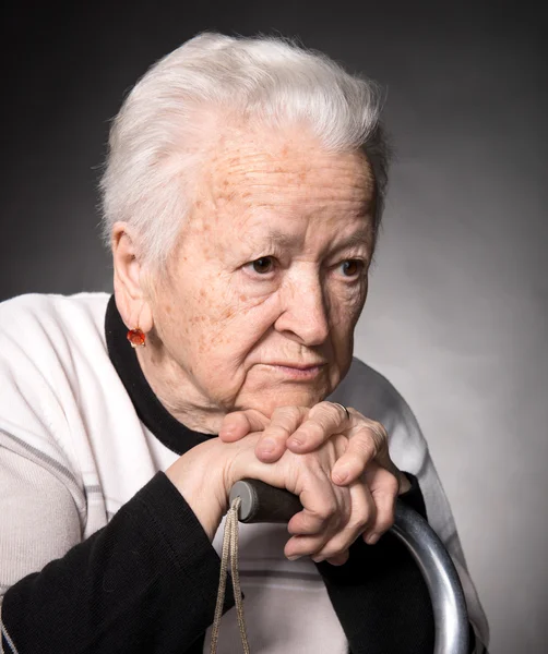 Portrait of old woman sitting with a cane