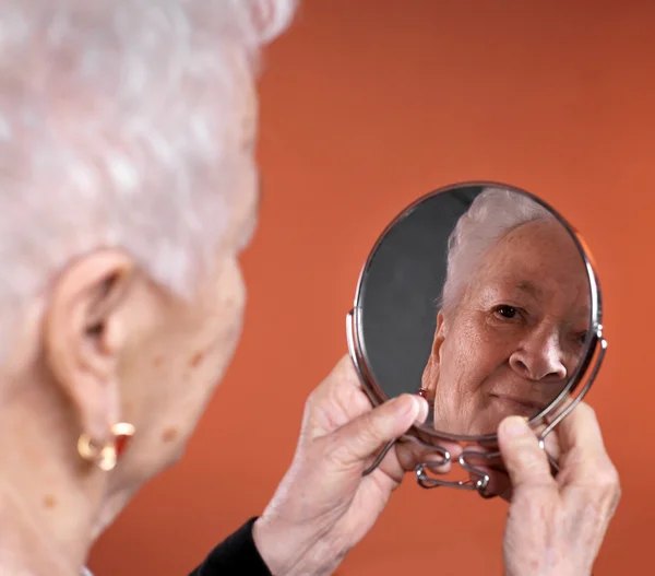 Portrait of old woman looking into a mirror