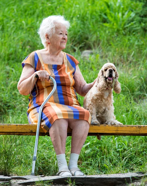 Old woman and her dog sitting on a bench