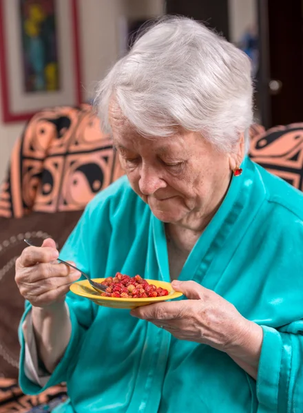 Old woman eating strawberry