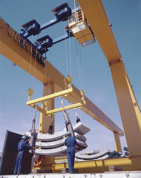 Overhead travelling crane with workers and precast segments.