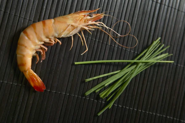 Cooked shrimp with black background and green plants