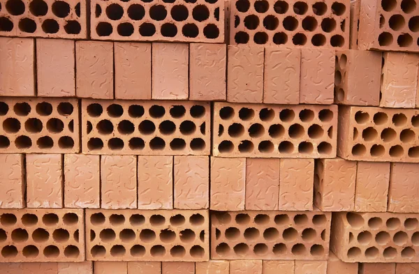 Stacked orange bricks for construction. Close up