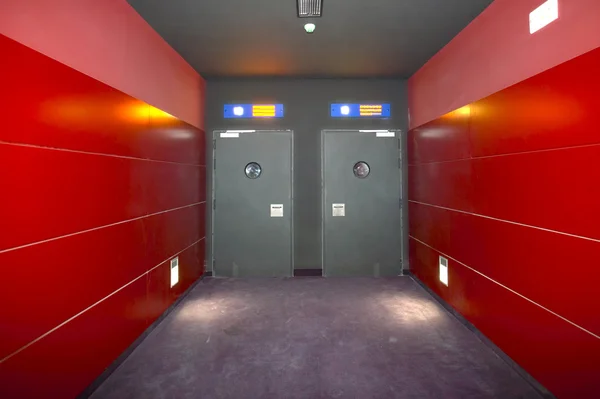 Two doors in a red corridor cinema room