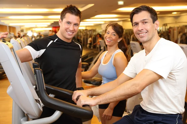 Three friends on exercise bikes in a gym