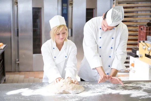 Baker instruction apprentice in kneading bread dough
